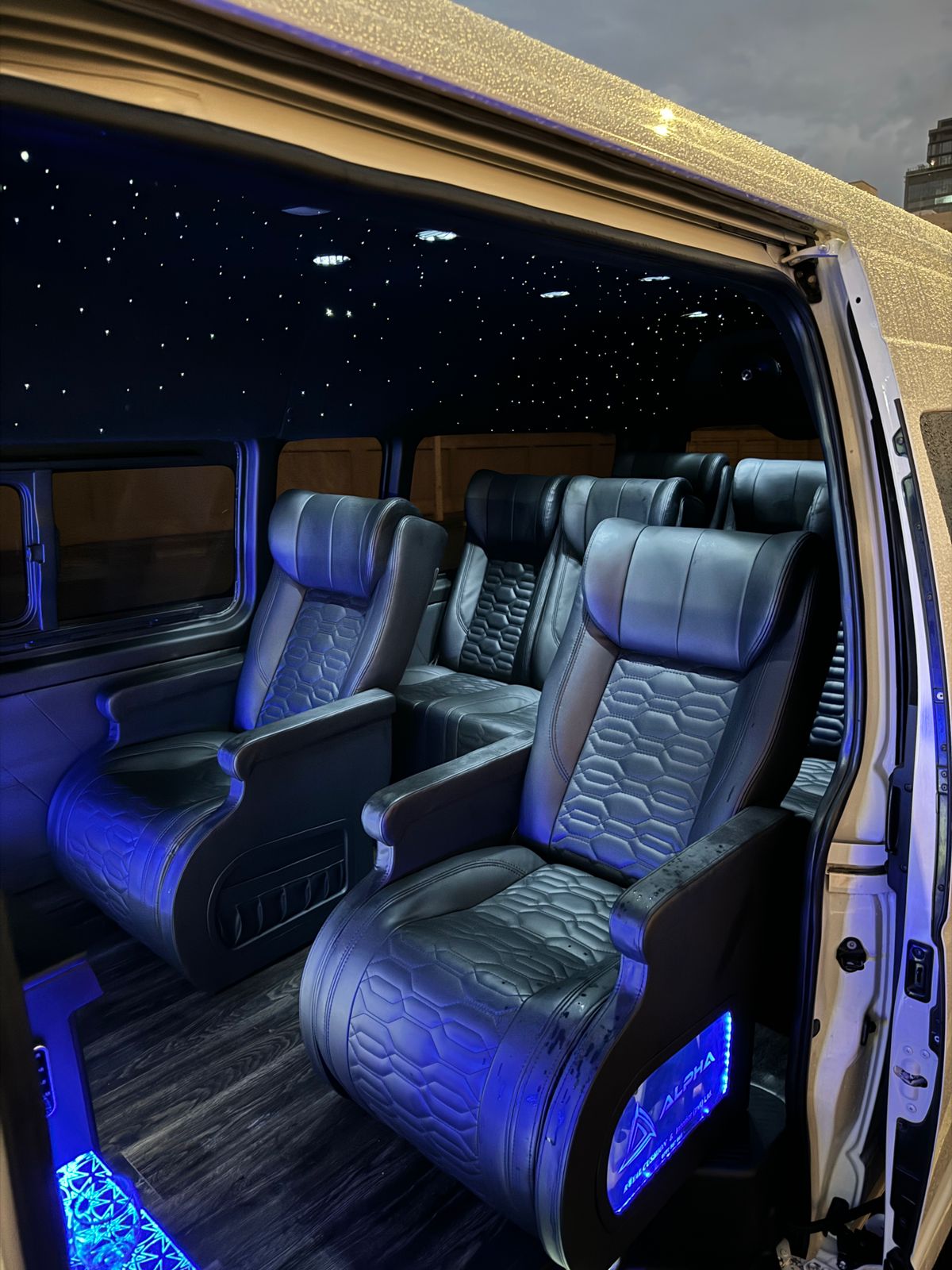 Van interior seating with ambient blue lighting and wood flooring