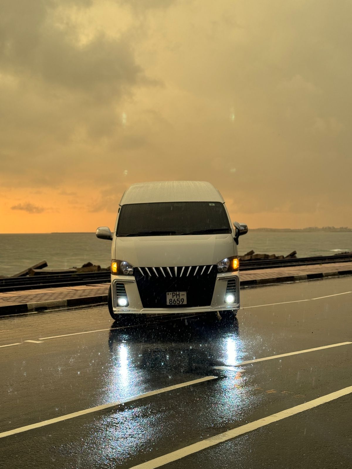 Front view of the Pinto Tours passenger van on a wet coastal road