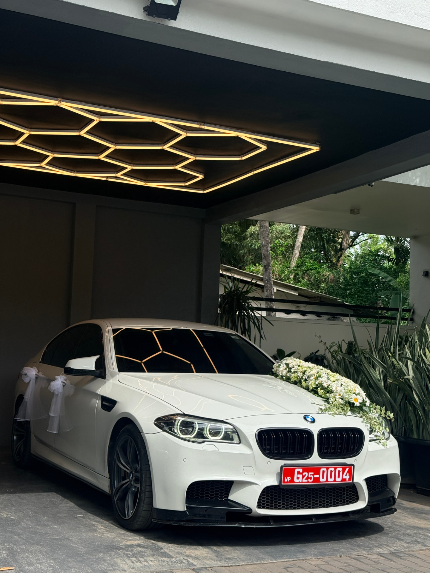 White BMW with floral wedding decoration under studio lighting